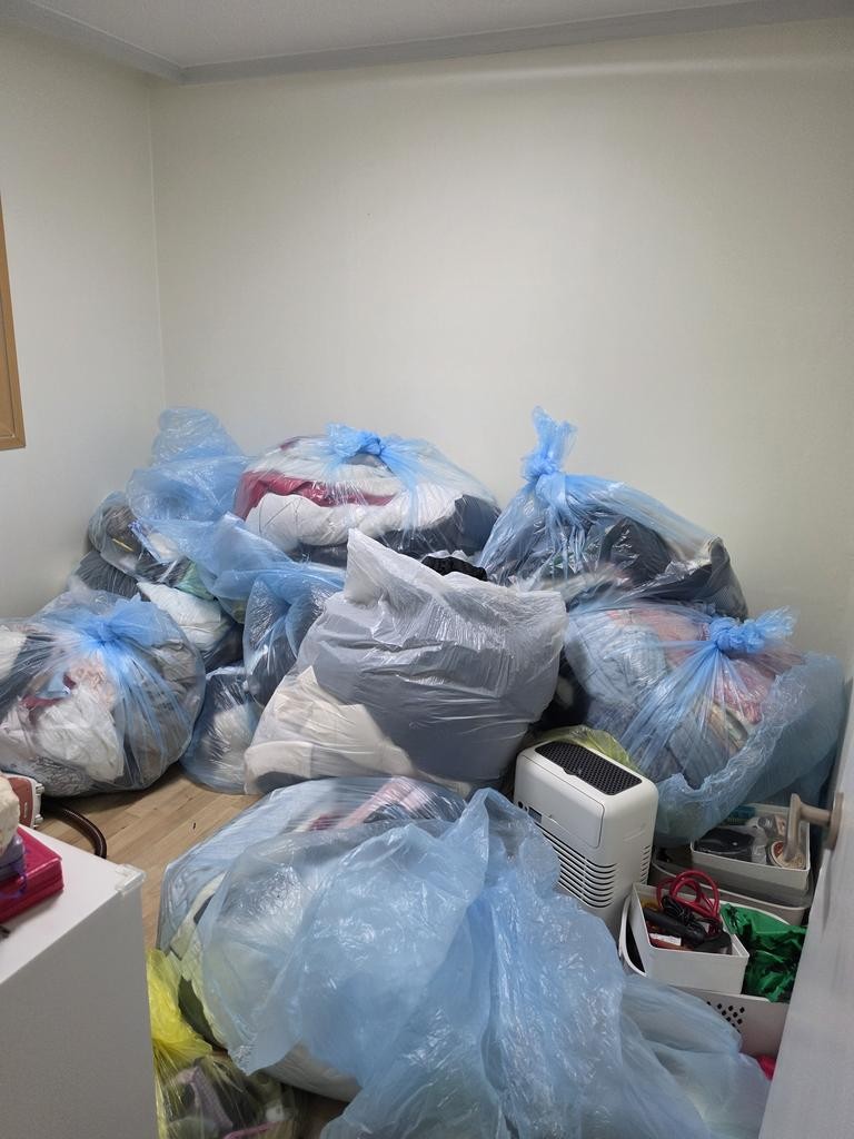 드레스룸 시공 전 빈방 바닥에 옷이 담긴 비닐봉투 여러 개가 쌓여 있는 모습.